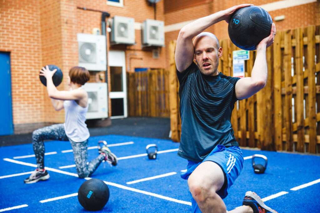 man and woman using slam balls to work out