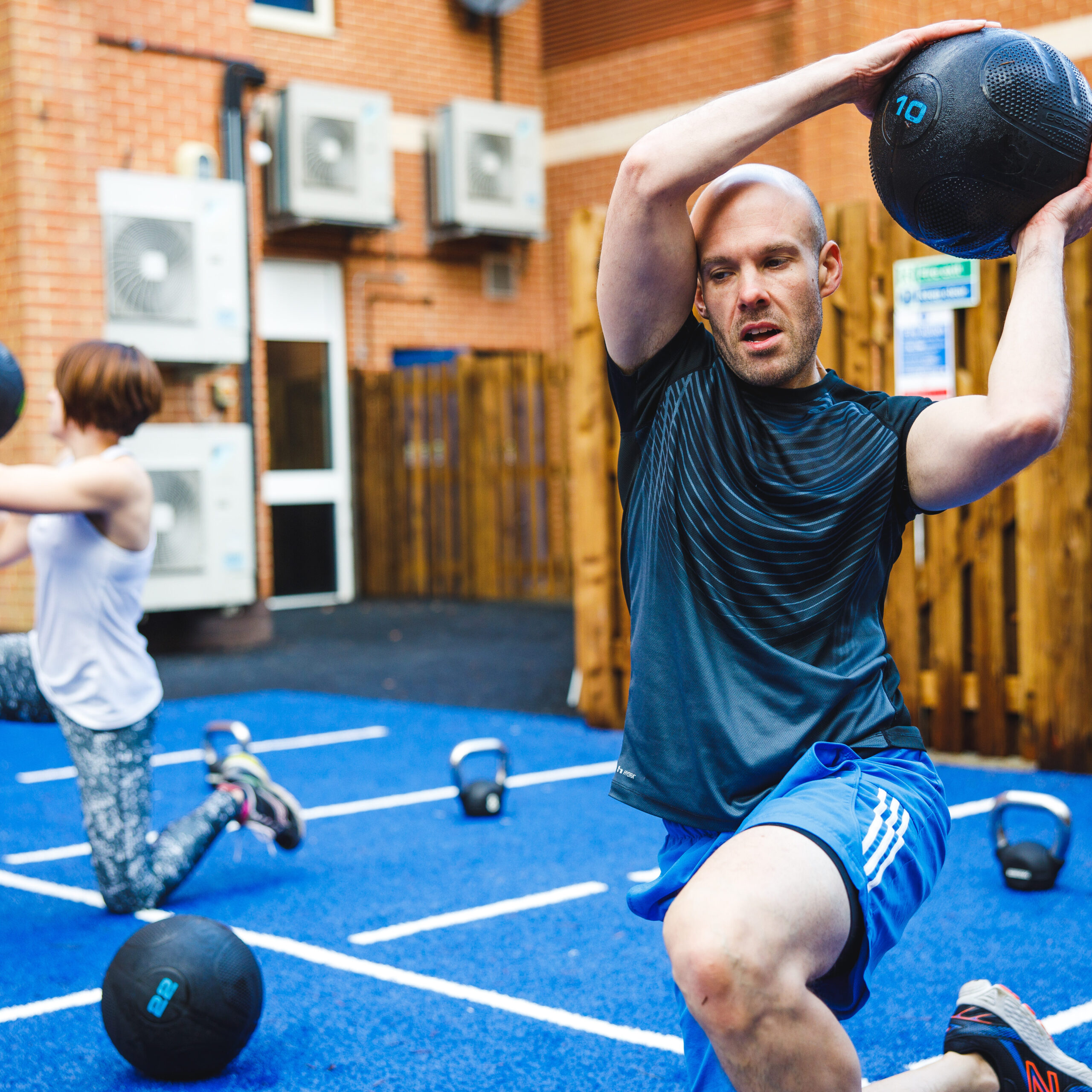 man and woman using slam balls to work out