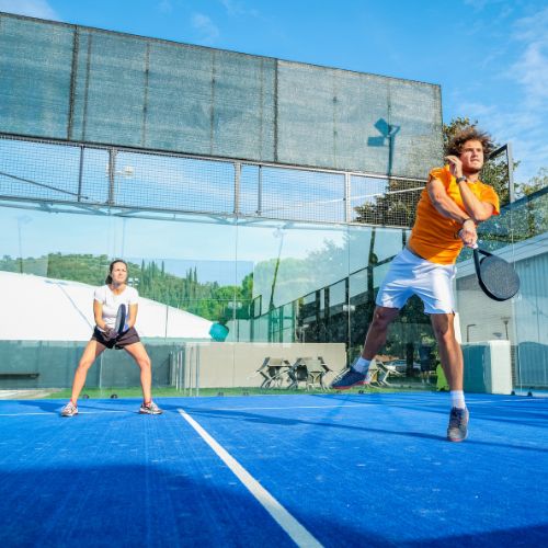 two people playing padel doubles jumping to hit the ball