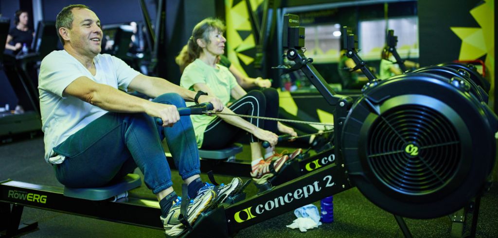 man and woman using the rowing machine